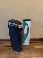 Front view of black device and green and white box showing air filter packaging.