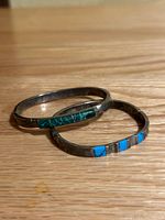 Two vintage Mexican sterling silver bracelets laid on wooden surface, showing turquoise and malachite stone inlays.