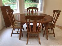 Full view of wooden dining table set including table and four chairs in a room by windows
