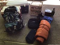 Overview of backpack, three coolers, sleeping bag, thermos, and black soft bags