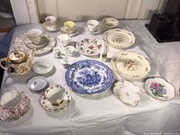 Full view of the mixed china collection including teapot, teacups, plates, egg cups, and serving dishes with floral and blue patterns.