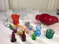 Front view of the collection showing various colored glass items including bowls, goblets, small bottles, and frosted glass pieces