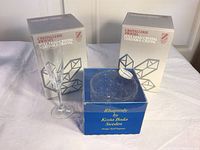 Two boxes of Cristallerie Zwiesel full lead crystal stemware and one box of Kosta Boda Rhapsody glass bowl. One glass stemware placed outside the box for display.
