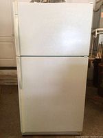 Front view of the white Kenmore top freezer refrigerator showing two doors with handles on left side.