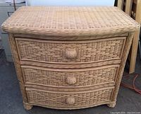 Front view of natural wicker dresser showing three woven drawers and natural light tan color.