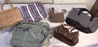 Overview of six assorted bags including tote bags, small purses, and duffle bag displayed on a white surface.