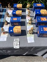 Eight M.I. Hummel figurines displayed with blue Goebel boxes and certificates on a table.