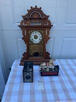 Full view of Seth Thomas clock, trick pony bank, Six-16 Brownie Junior camera on checked cloth