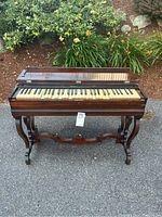 Front view of antique wooden Prince & Co. Melodeon C keyboard showing all ivory and black keys, some uneven and discolored, with carved wooden legs and stretcher base.