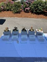 Five Hummel seasonal figurines in a row on white foam packaging with certificates of authenticity on the table.