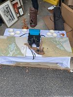Full layout of the lot showing maps spread out, binoculars with case, seashells arranged in rows, decorative metal item, and driftwood pieces.