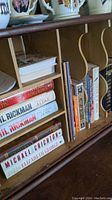 Books placed on wooden cubby shelf showing titles including George R.R. Martin's "A Feast for Crows" and others.