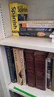 Photo showing a variety of books including a Spanish language course, dog adoption and training guides, and dictionaries on a bookshelf.