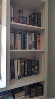 Bookshelves with multiple books including fantasy and historical novels arranged vertically and horizontally.