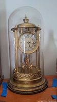 Full view of the vintage anniversary clock with glass dome, showing dial and base.