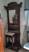 Full view of the wooden hall stand showing the mirror, hooks, shelf, and marble top.