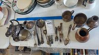 Lot contents including a sterling weighted teapot, several spoons and forks, and multiple small vessels and candle holders.