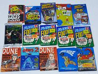 Top view showing front of all 15 unopened wax packs featuring diverse themes including sports, movies, cartoons, and pop culture.