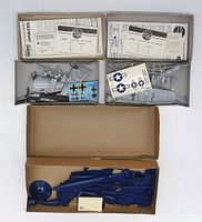 Boxes and contents of three vintage airplane model kits, pieces and decals visible