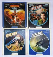 Four Star Trek laserdisc covers in plastic sleeves showing artwork for The Motion Picture, Balance of Terror, and two for The Menagerie.