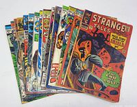 Photo showing a spread of 16 vintage Marvel comics stacked and fanned, covers include Strange Tales with Nick Fury, condition shows wear and discoloration.