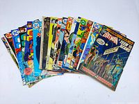 Photo showing 19 vintage DC Comics laid out fanned, titles include Batman and Teen Titans, Justice Inc among others. Covers show wear and use.