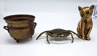 Front view showing the small brass pot, brass crab, and brass cat figurine arranged in a row