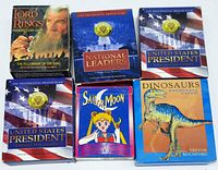 Photo of all six card sets in their original packaging arranged side by side showing front cover art and titles.