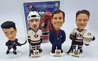 Front view of four NHL bobblehead figures including Kariya, Yzerman, Gretzky, and Joseph, plus the mini Canada sweater in packaging behind