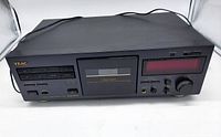 Front view of TEAC V-1030 cassette tape player/recorder showing control buttons, cassette door, and display.