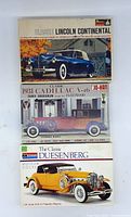 Three classic car model kit boxes stacked showing Lincoln Continental, 1931 Cadillac V-16 Town Brougham, and Duesenberg.