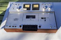 Front view showing the full front panel with cassette slot, VU meters, knobs, switches, and wood side panels.