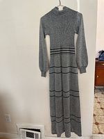 Front view of one vintage long metallic knit dress in silver-gray with black horizontal stripes, high neck, and long sleeves.
