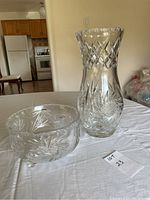 Photo showing crystal vase and footed dish together on a white tablecloth with kitchen background.