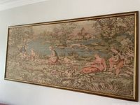 Framed Italian tapestry on wall showing pastoral scene with figures near a lake and village, detailed woven artwork