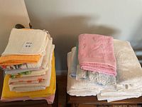 Stack of various bath towels including yellow, white with pattern, purple and orange towels all stacked on a small wooden stool.
