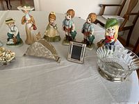 Image showing a front row of ceramic figurines of children and small decorative metal and glass items