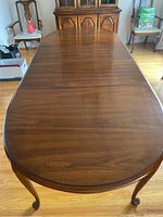 Top down view of oval wood dining table with visible grain and two extension leaves joined in the middle.