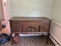 Front view of 1970s wood buffet with four drawers, carved center drawer, and cabriole legs on wood floor.