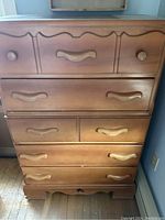 Front view of vintage wooden dresser showing drawer arrangement and wooden handles.