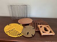 Various hot plates and cooling racks on a wooden surface, showing their different materials and shapes