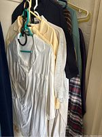 Photo showing multiple hanging men's shirts in various colors including white, cream, navy, and patterned shirts.