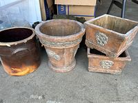 Photo of four garden planters on garage floor showing terra cotta and ceramic materials and weathered condition.