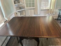 Top view of rectangular solid wood table with two extended leaves and smooth wood grain finish.