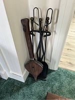 Photo showing the full view of all fire tools including the wooden and leather bellows, metal poker, shovel, and the black metal stand.