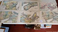 Photo showing six old folded maps laid out on a surface, each with different regional coverage of the Dominion of Canada with pastel county colorings