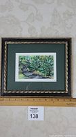 Photo of full framed artwork showing green matting and decorative frame with ruler for scale
