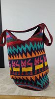 Front side view of the colorful crochet bucket bag showing geometric and animal patterns.
