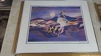 Framed Indigenous art print in a white frame without glass showing colorful artwork with a white horse, mountains, and full moon.