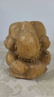 Front view of the solid carved wood yogiman figure showing bowed head and detailed hands and feet.